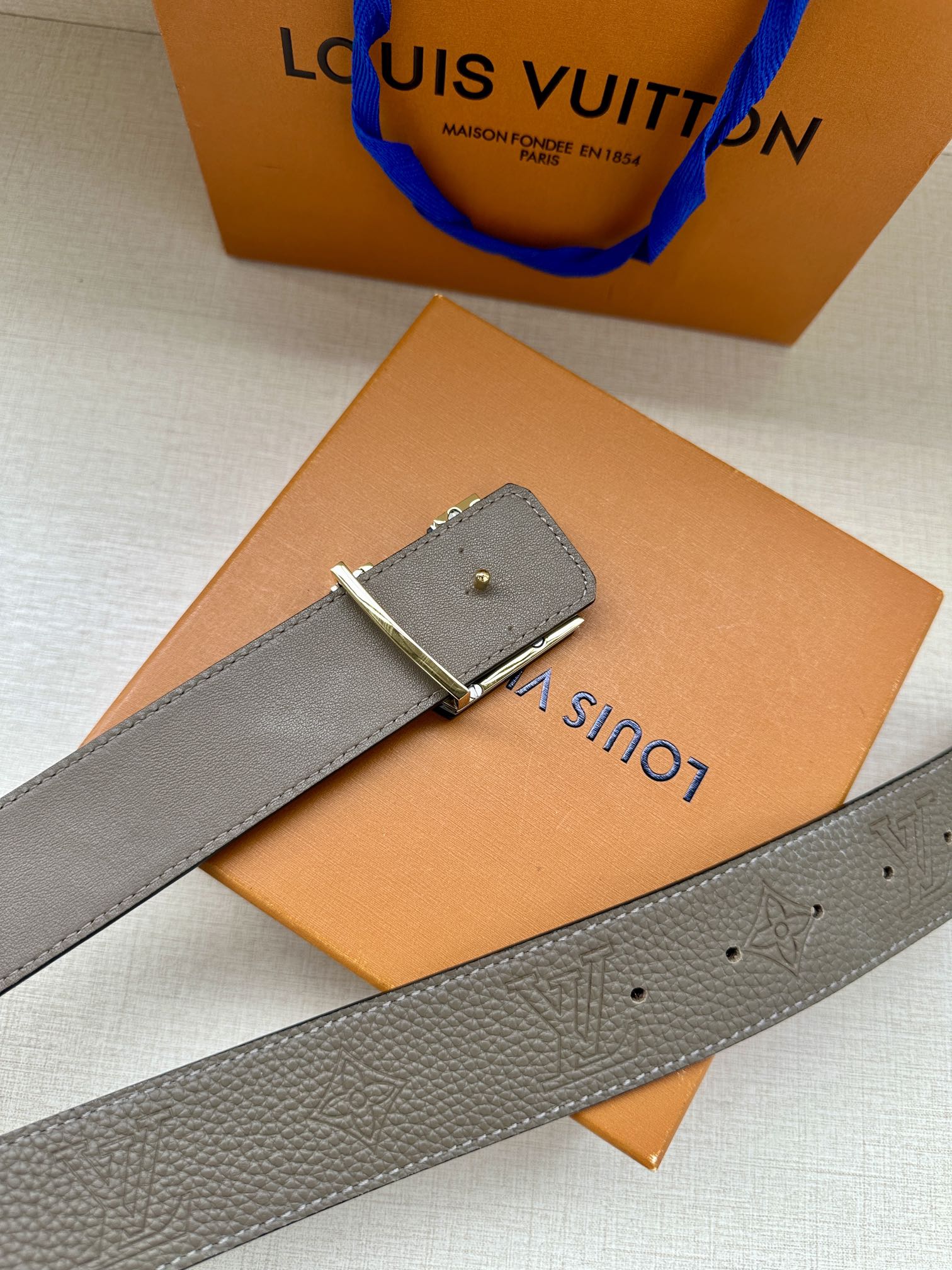 Gray leather belt with metal clasp and LV buckle detail