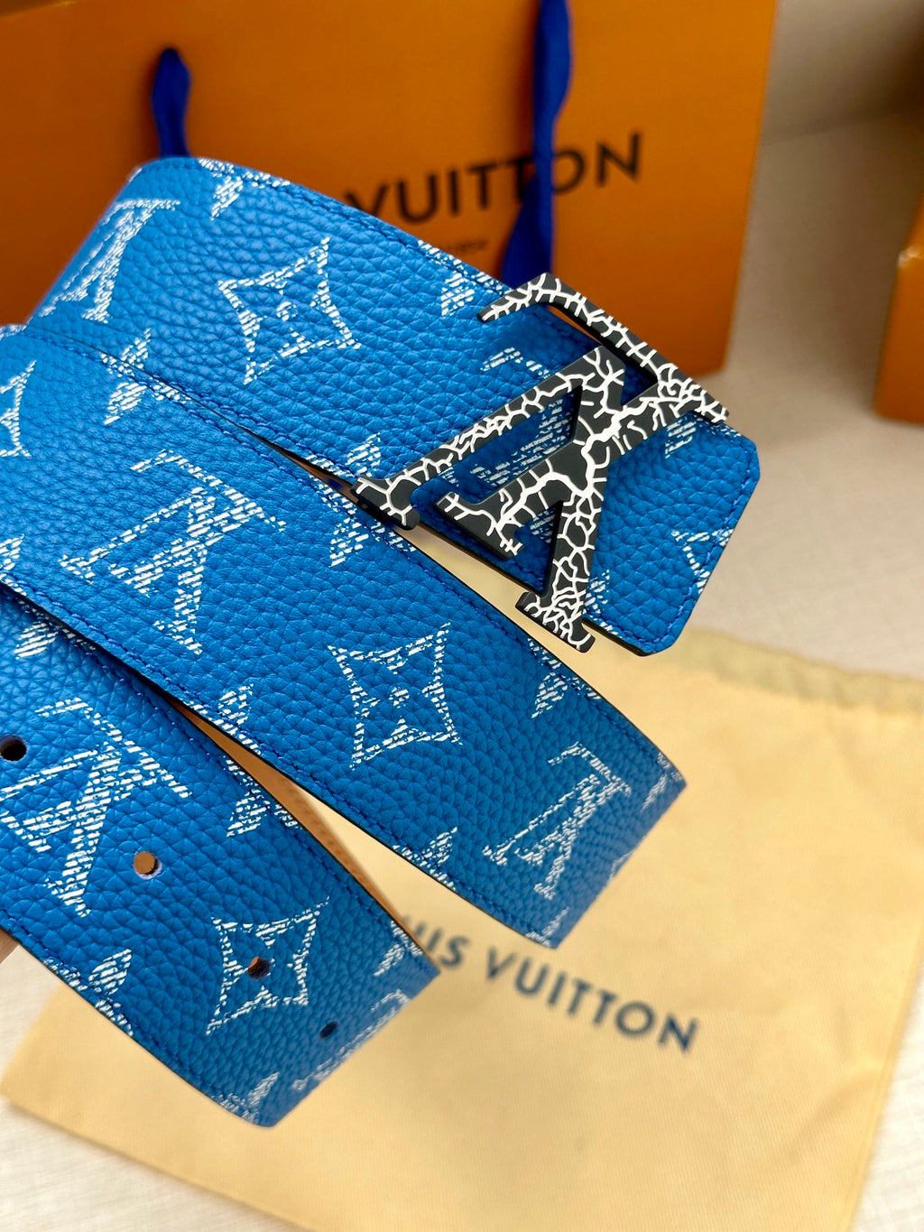 Blue monogram belt with detailed metal buckle and textured strap