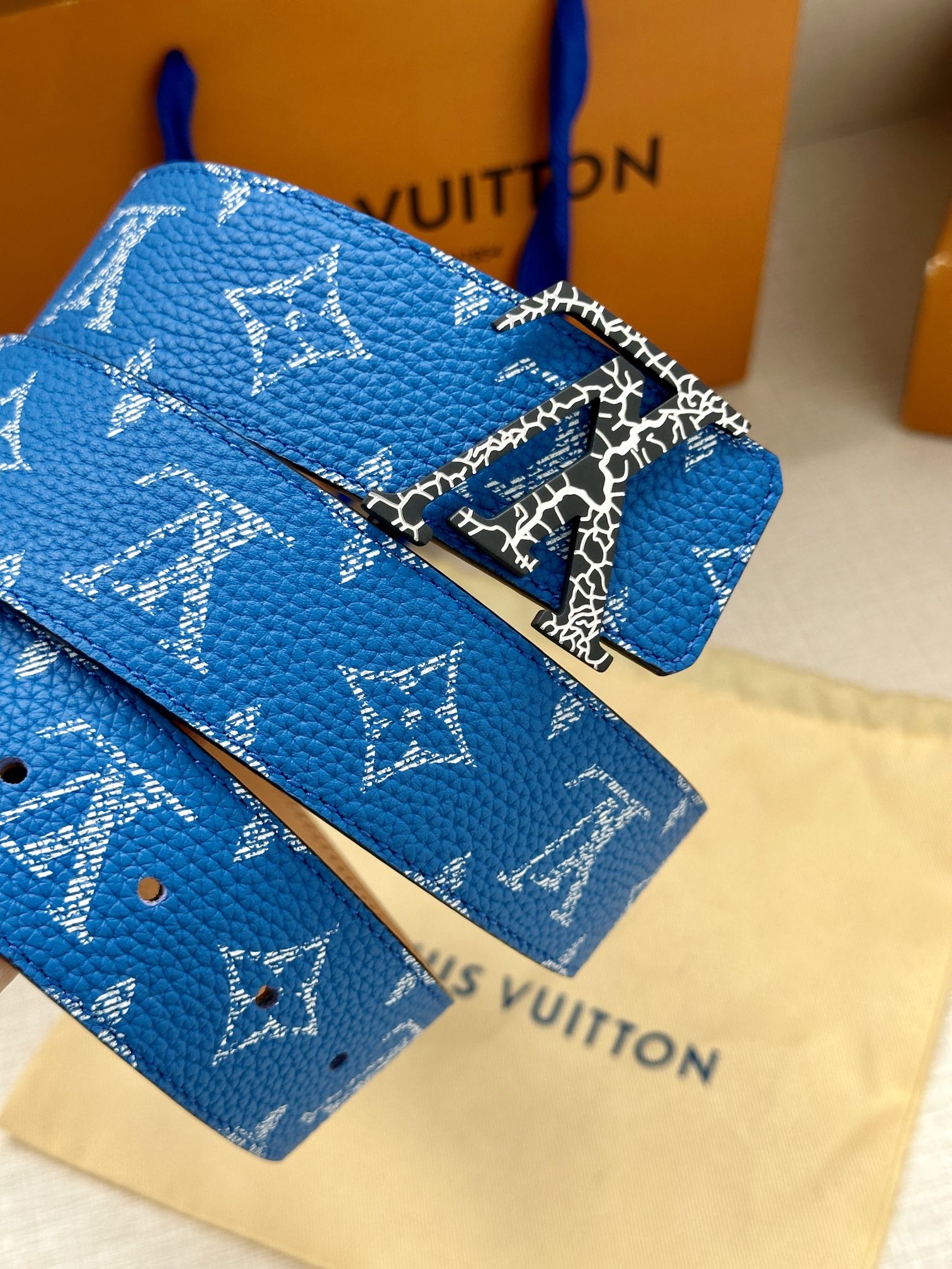 Blue monogram belt with detailed metal buckle and textured strap