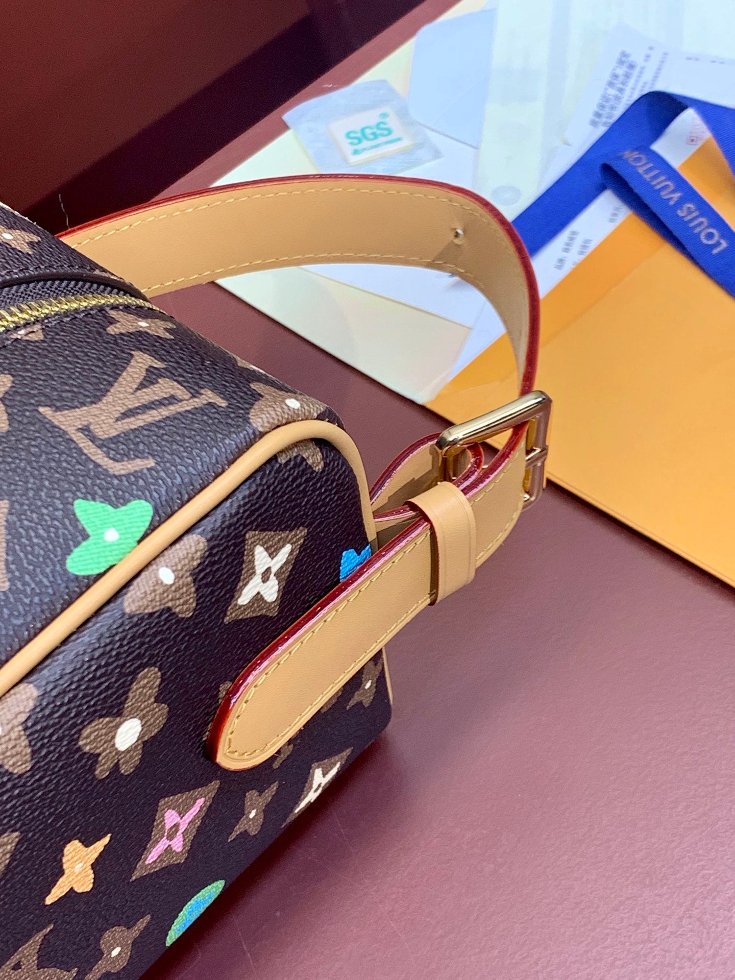 Monogram bag strap and brass buckle with tan edging and multicolor star motifs