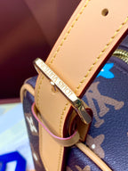 Tan leather strap attachment with gold buckle on navy monogram bag exterior