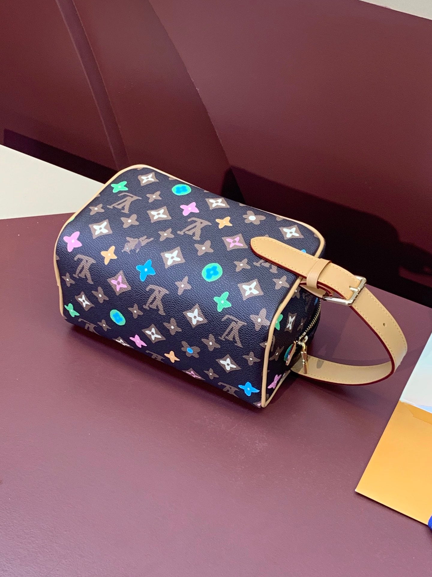 Monogram zip bag with multicolor star icons and light tan crossbody strap