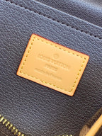 Leather brand patch on dark monogram bag, tan background with gold lettering