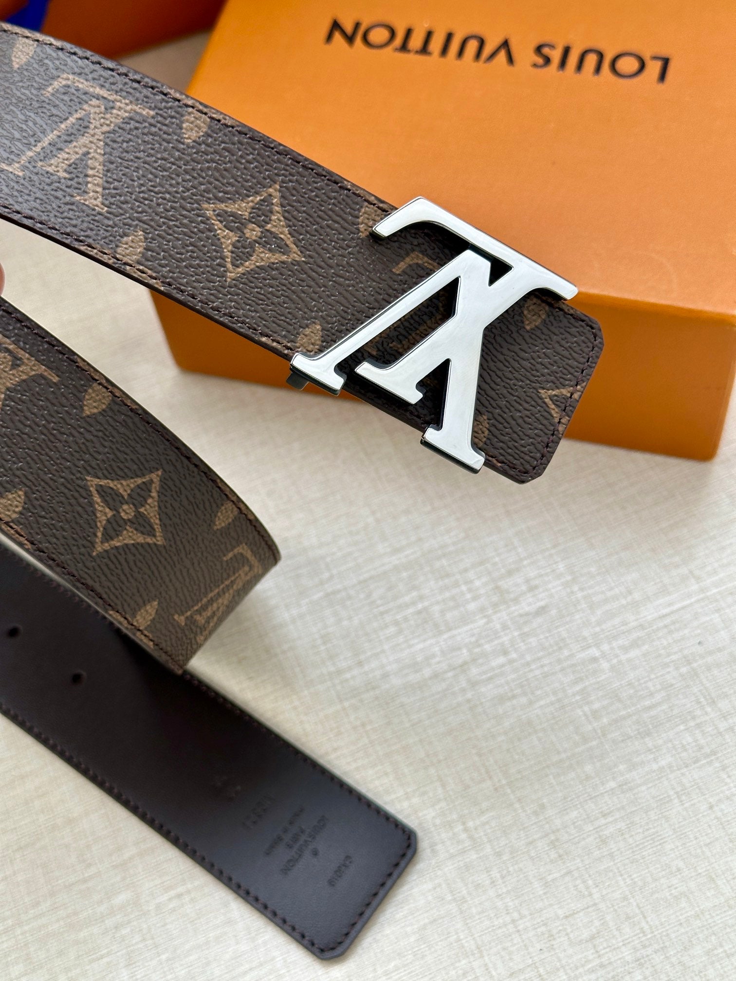 Monogram belt with white-metal LV buckle and dark leather strap holes