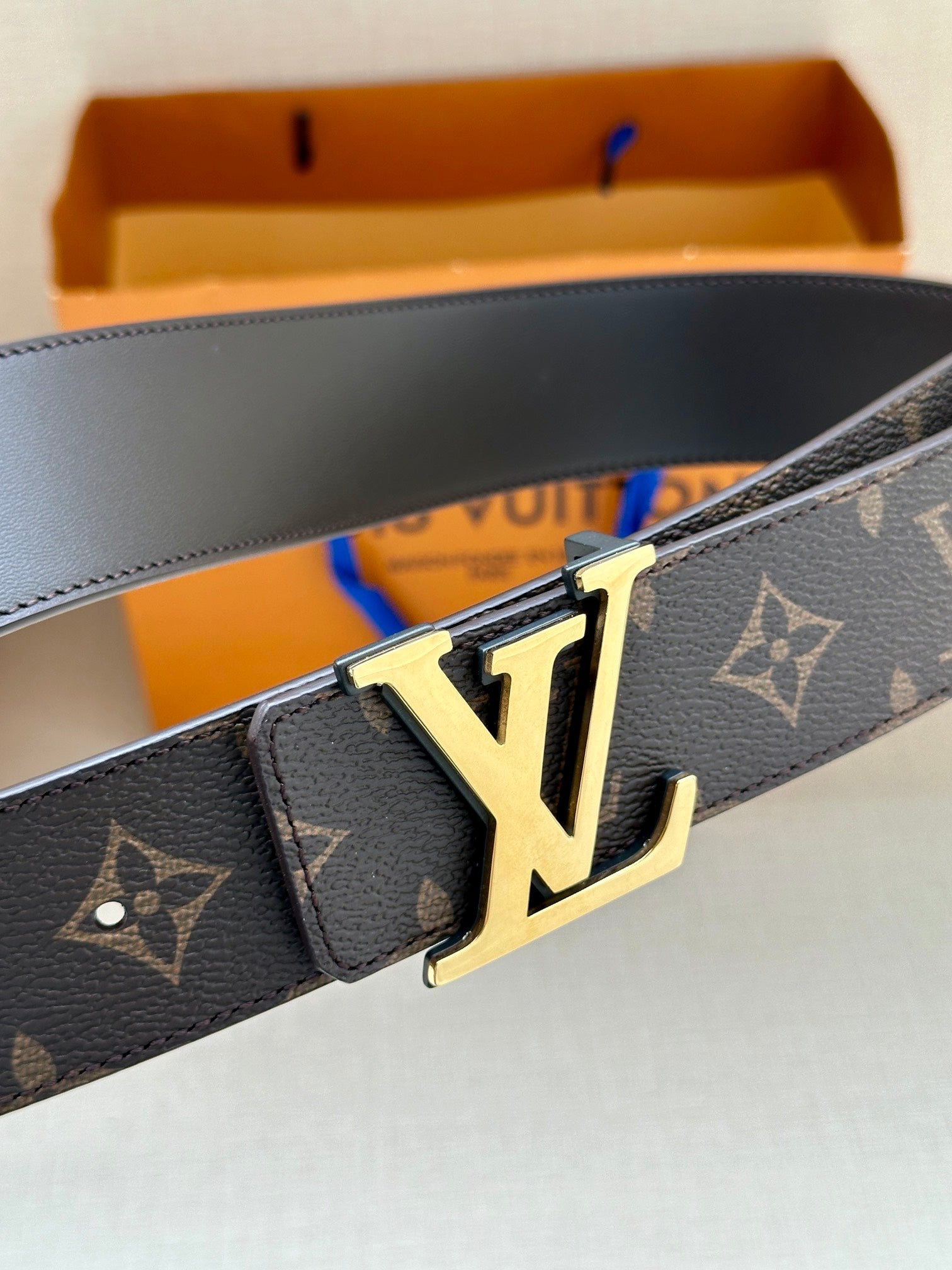 Louis Vuitton monogram belt closeup with gold-tone LV buckle and keeper