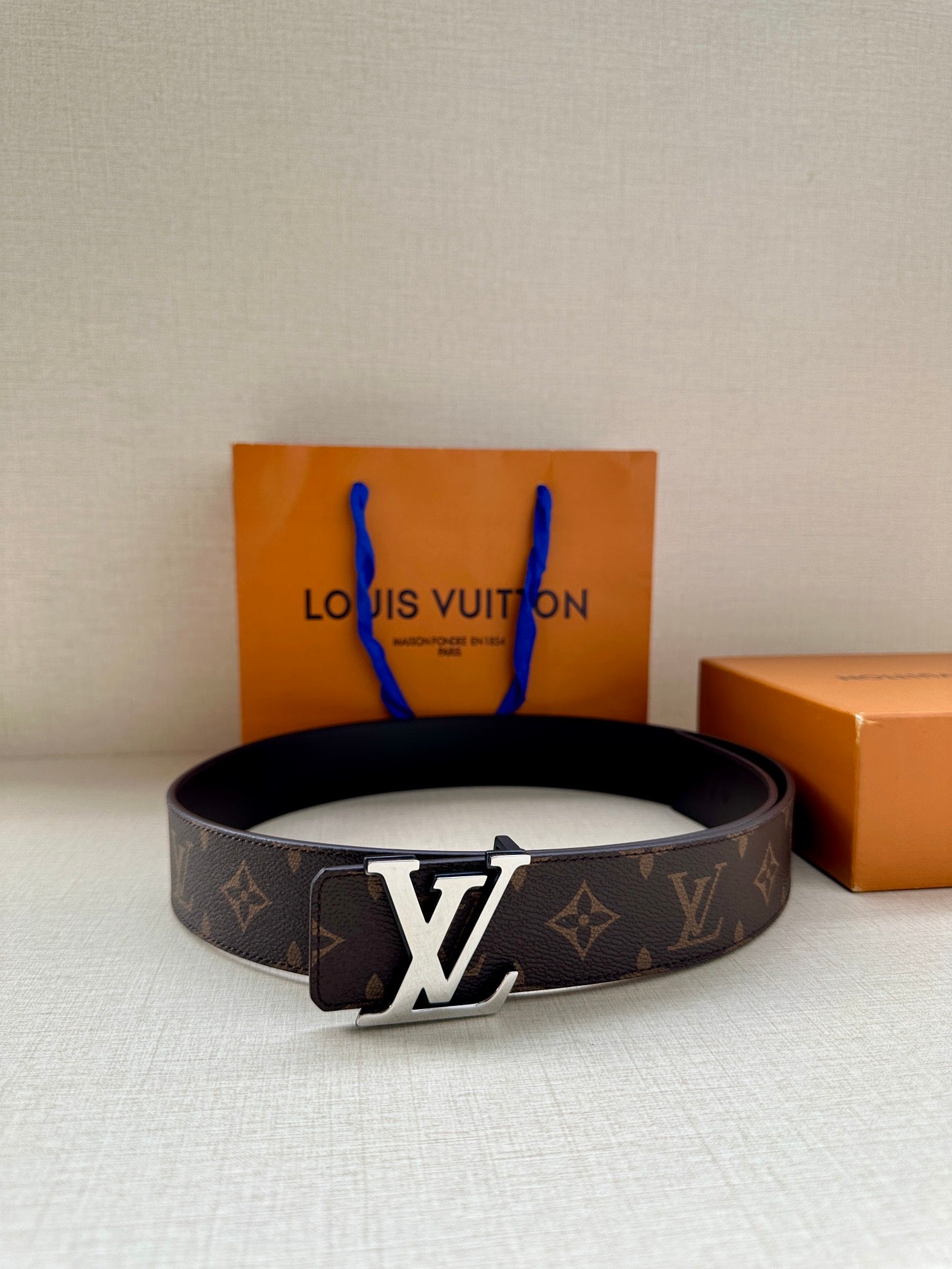 Louis Vuitton monogram belt with LV buckle and center crossbar, dark strap