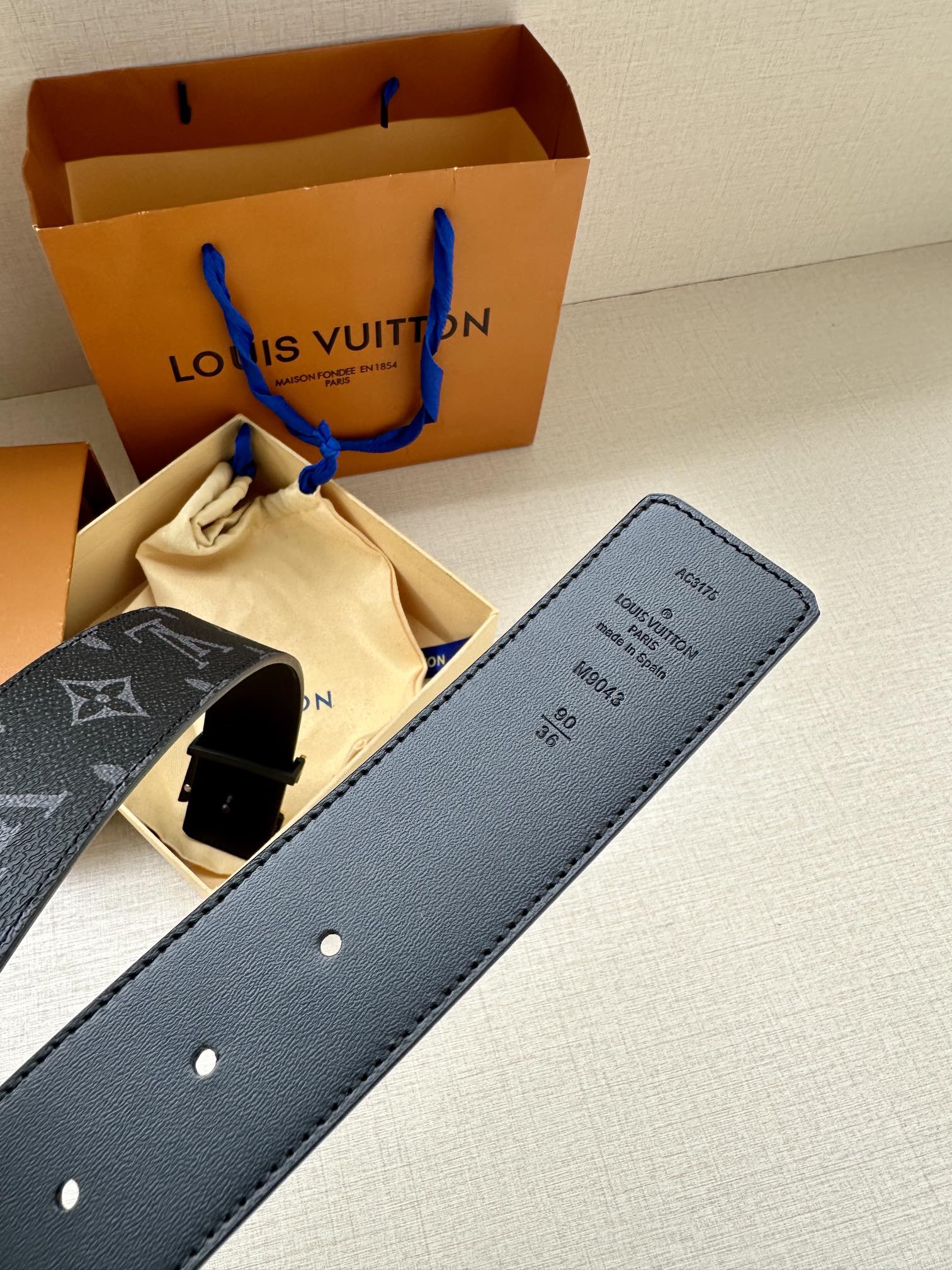 Navy monogram belt interior with engraved sizing tag and silver holes