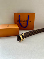 Louis Vuitton belt with damier pattern and gold-tone LV buckle, lying diagonally