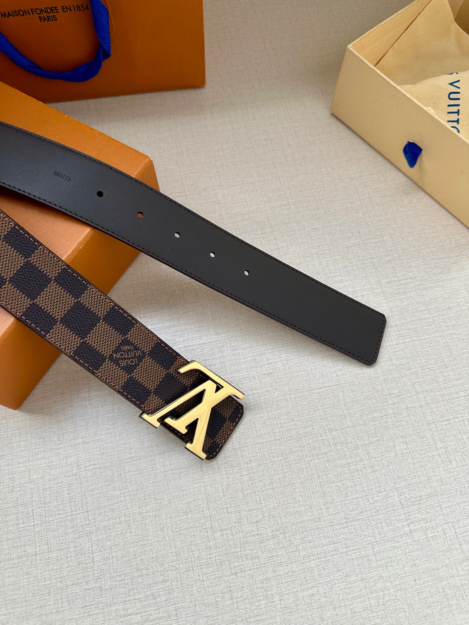 Louis Vuitton belt strap end with dark leather, perforation holes, and gold-tone buckle