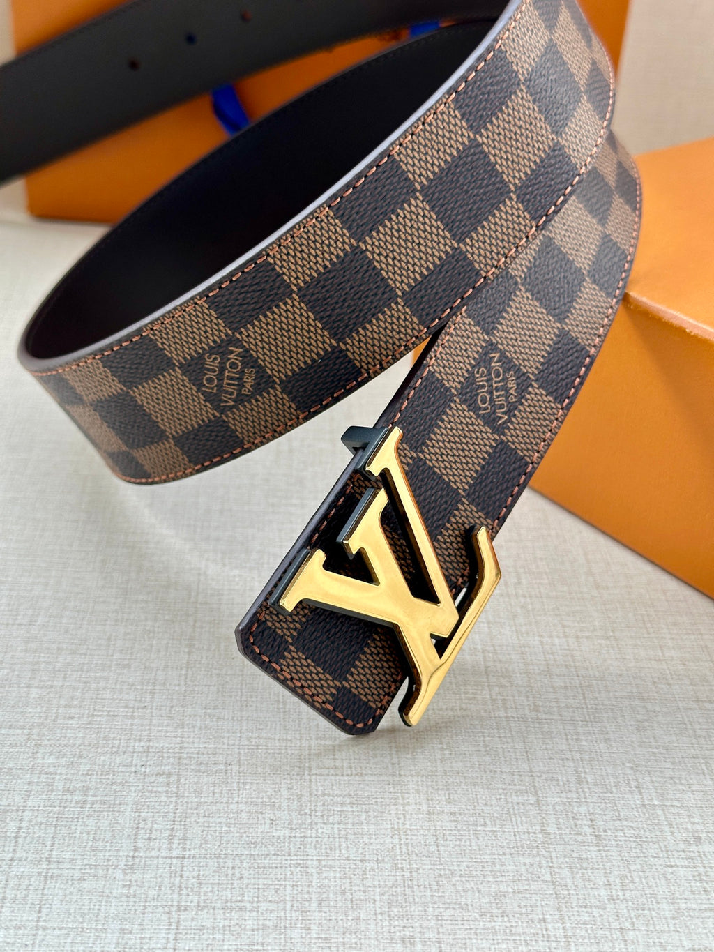 Louis Vuitton belt close-up of LV buckle on damier check strap, dark lining