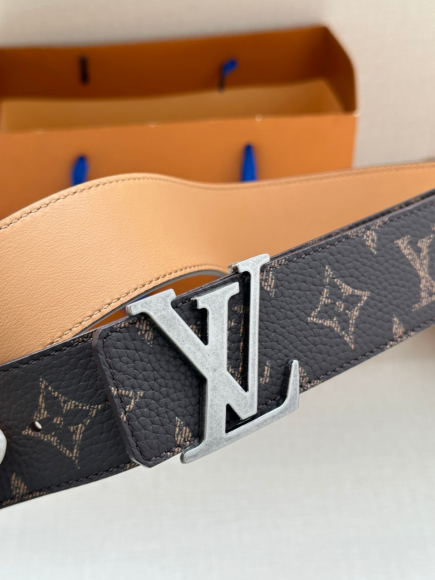 Louis Vuitton monogram belt close-up, silver LV buckle on dark canvas with star motif.
