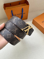 Louis Vuitton monogram belt held in hand, dark canvas strap with silver LV buckle and tan side.