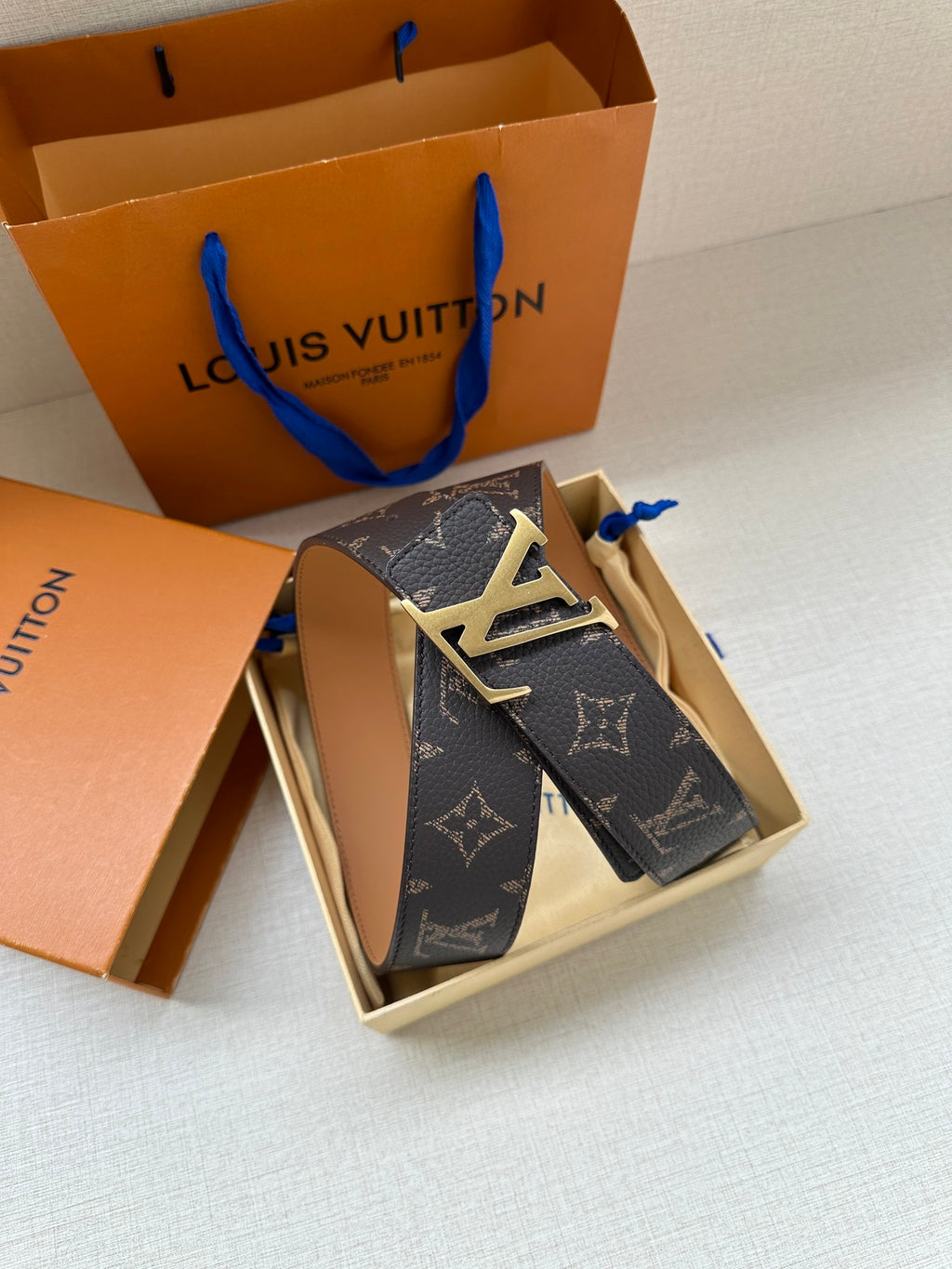 Louis Vuitton monogram belt with silver-tone LV buckle, dark canvas strap and tan inner surface.