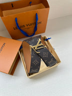Louis Vuitton monogram belt with silver-tone LV buckle, dark canvas strap and tan inner surface.