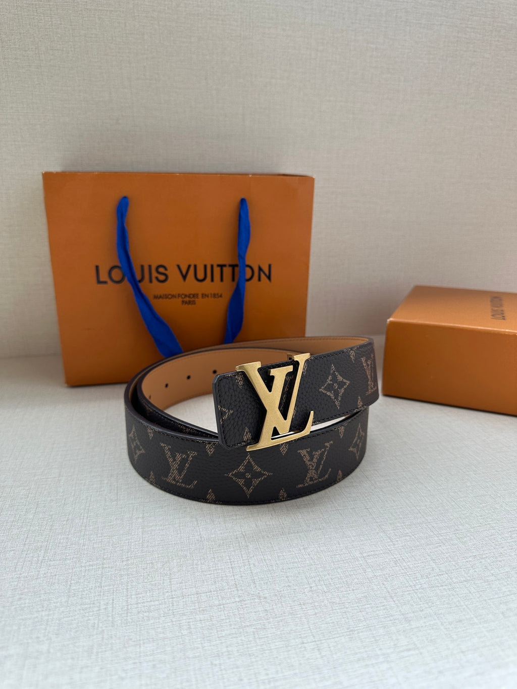 Louis Vuitton monogram belt with silver LV buckle, dark canvas strap and tan leather lining.