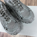Gray Balenciaga sneakers showing mesh panels, lace-up front, and chunky tread midsole