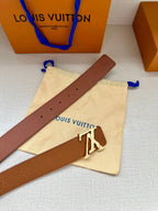 Tan leather belt with silver buckle laid across a dust bag and box