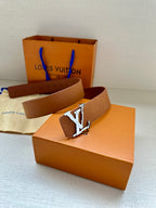 Tan monogram leather belt with silver buckle resting on an orange box