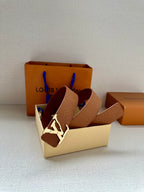 Tan monogram leather belt set with silver buckle inside an open box
