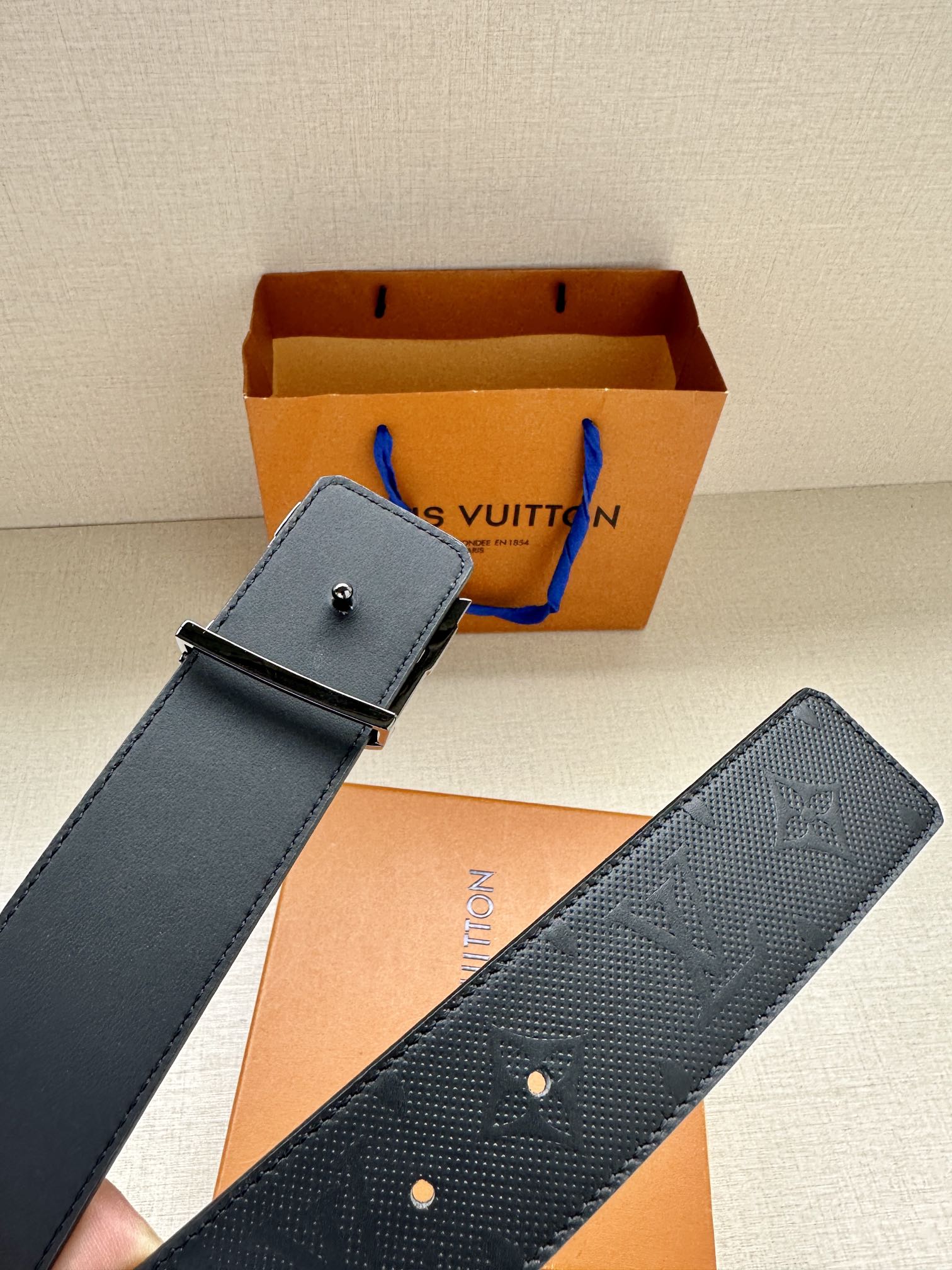 Blue leather belt with embossed pattern and silver LV buckle on strap