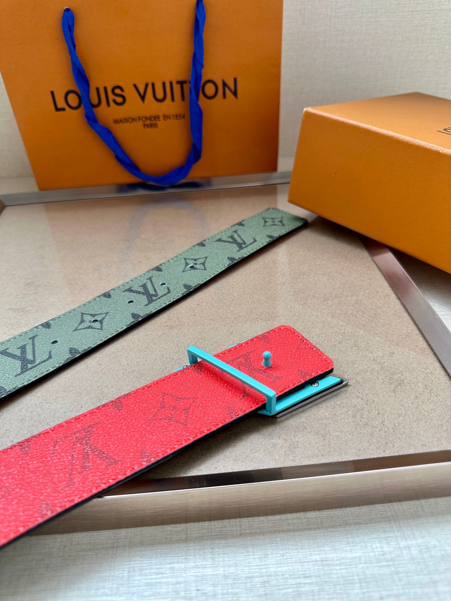 Louis Vuitton belt detail, green monogram strap with silver LV buckle and red lining
