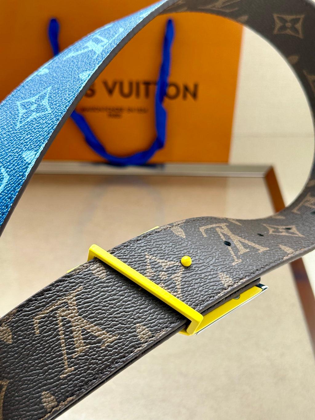 Louis Vuitton belt with blue monogram strap, brown leather section, yellow-edged buckle