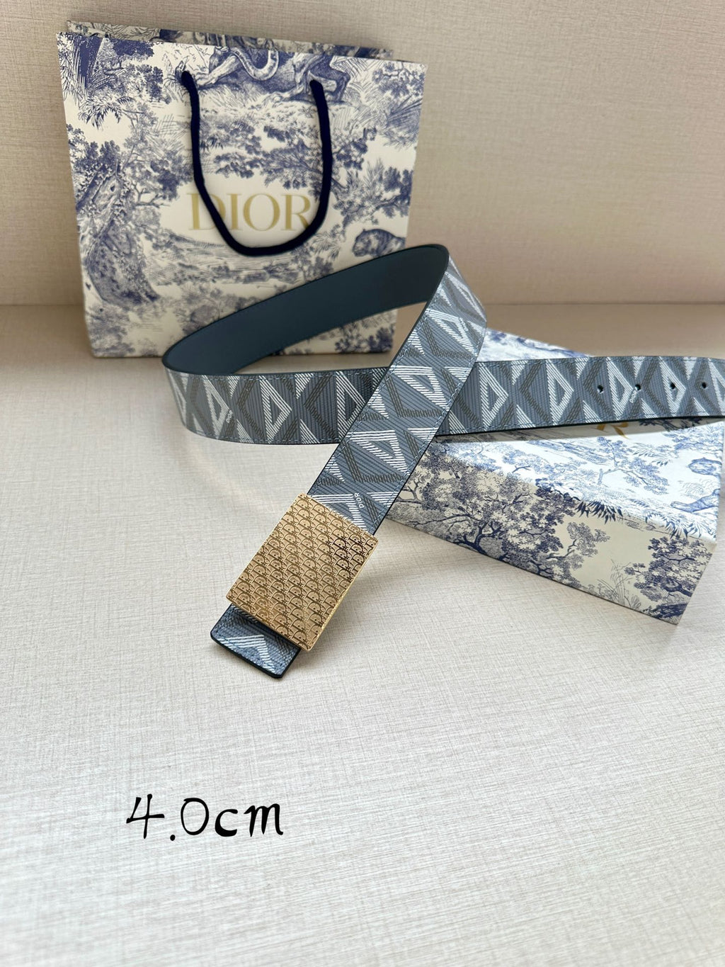 Dior belt with patterned strap and gold-tone buckle, laid flat with tag