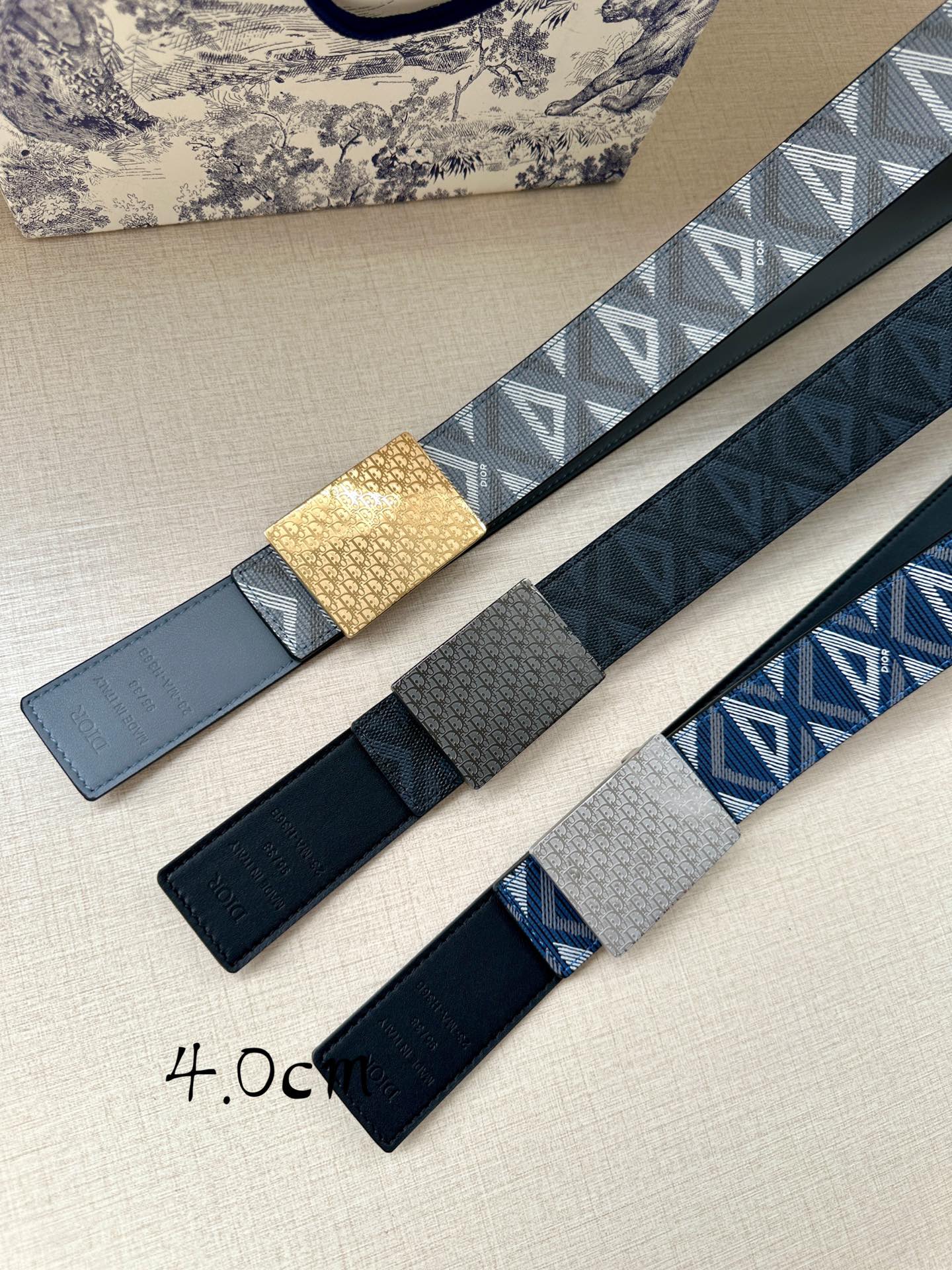 Dior belts shown side by side, blue and dark straps with gold-tone buckle