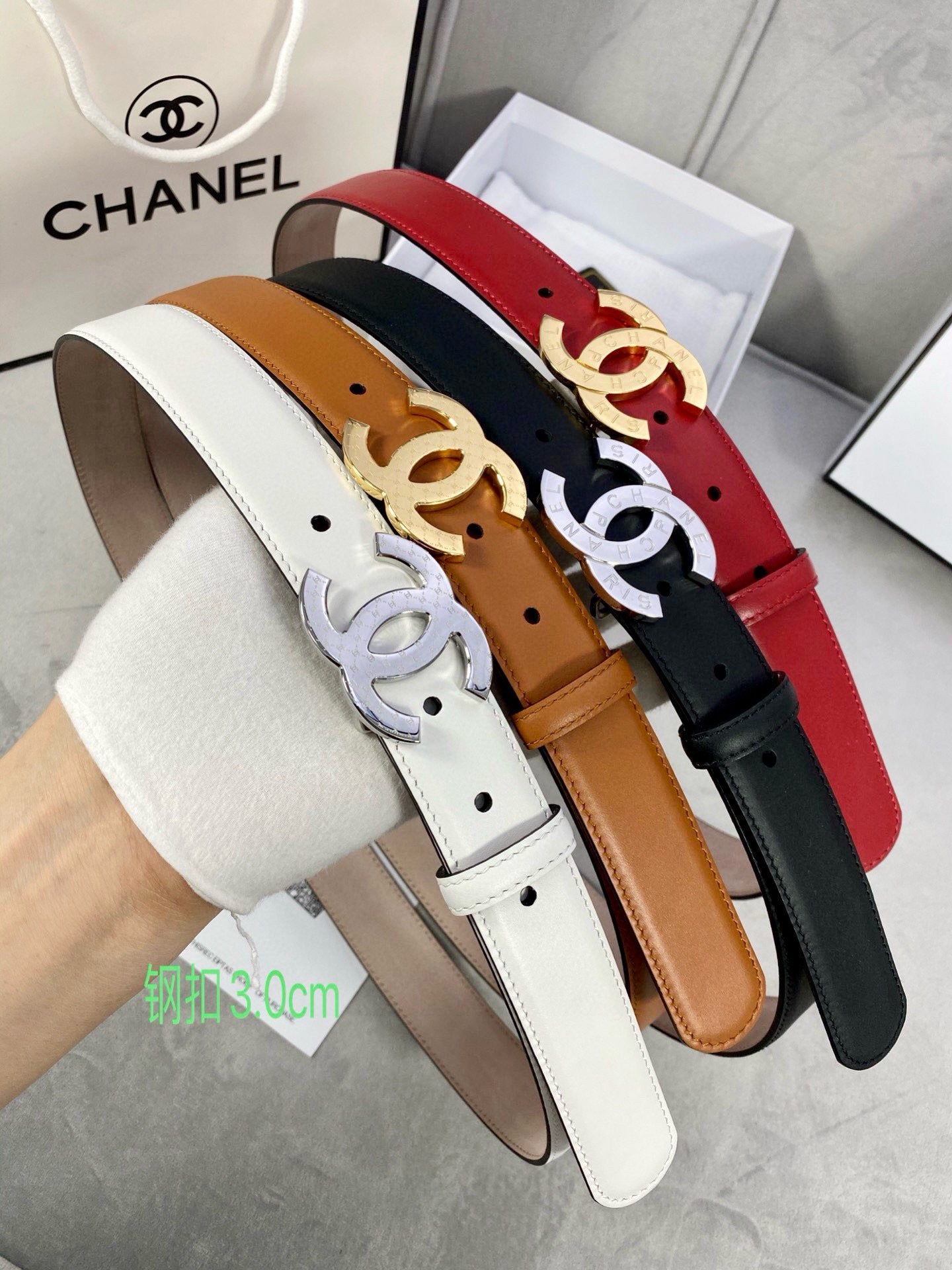 Three leather belts with CC buckles in black, white, and red