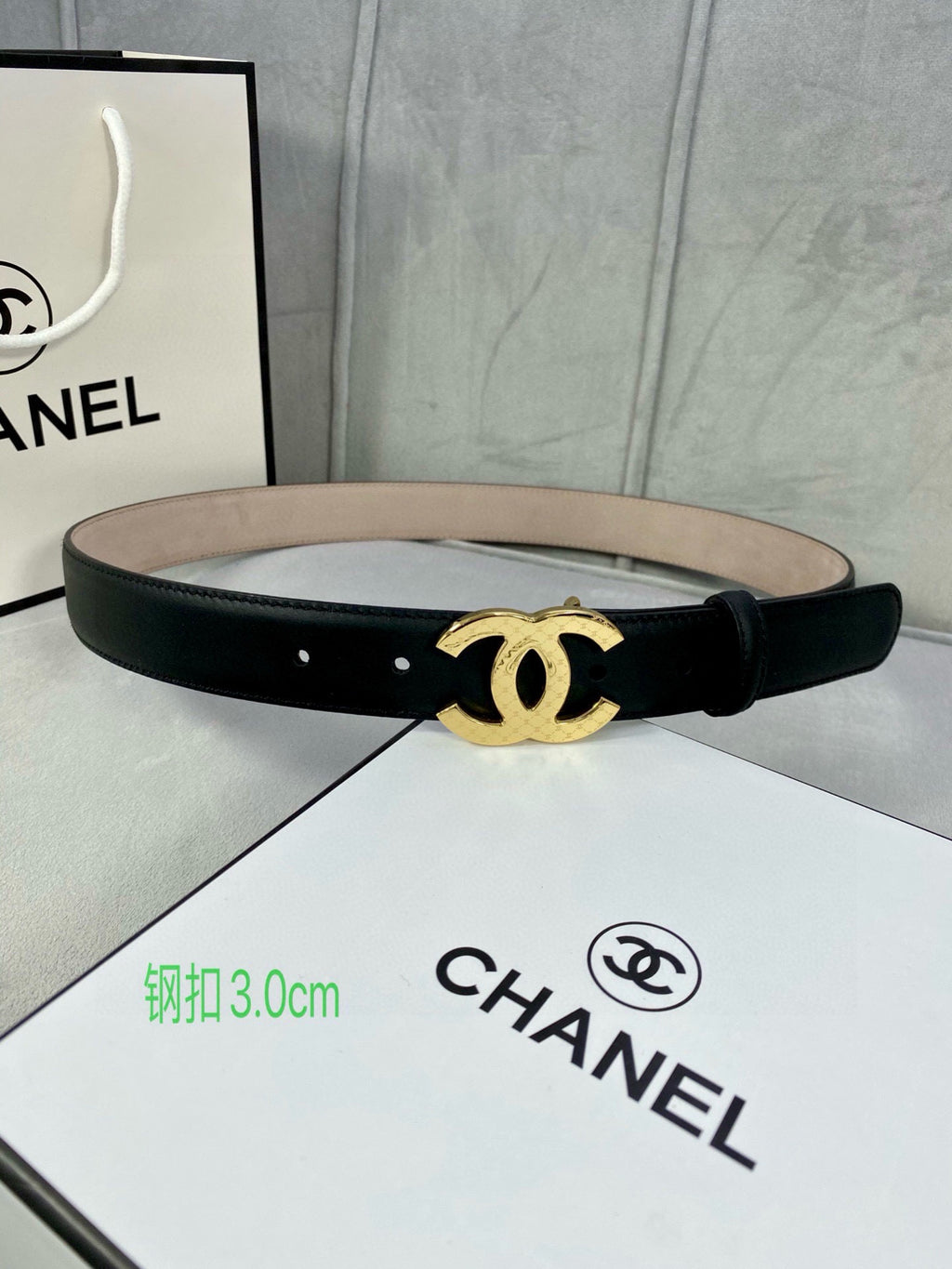 Black leather belt with gold-tone CC buckle laid across box insert