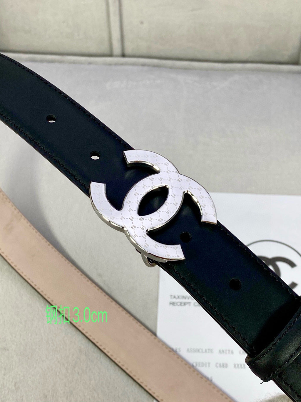 Black leather belt close-up with silver-tone interlocking CC buckle