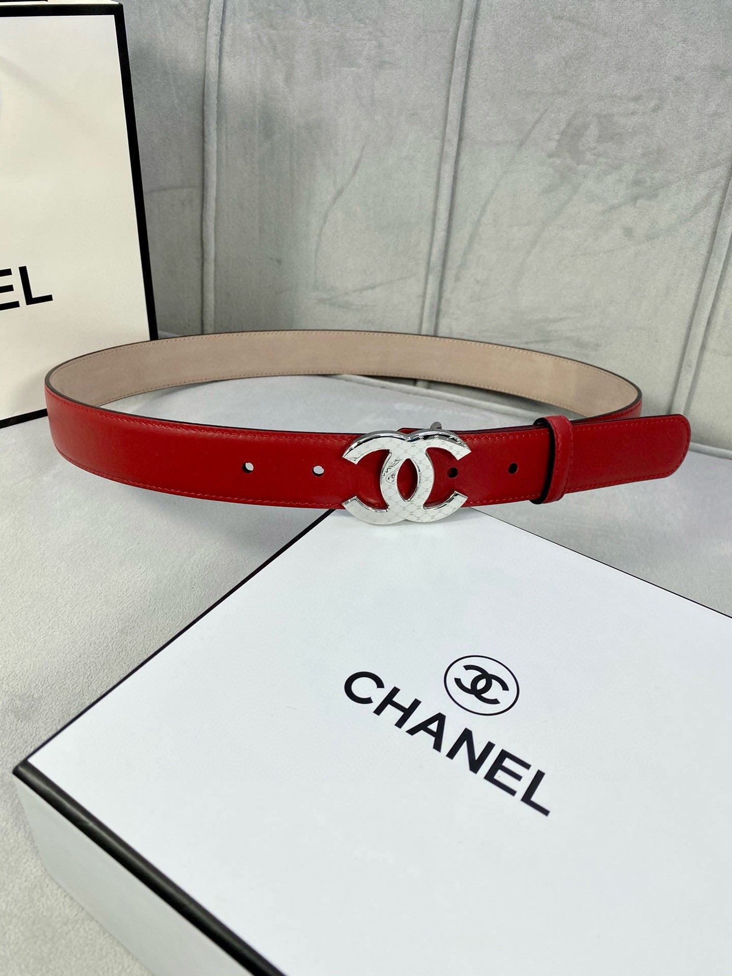 Chanel belt in red leather with silver-tone double C buckle on straight strap.