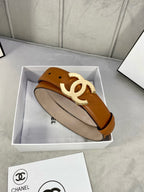 Tan leather belt with gold-tone CC logo buckle resting in a box