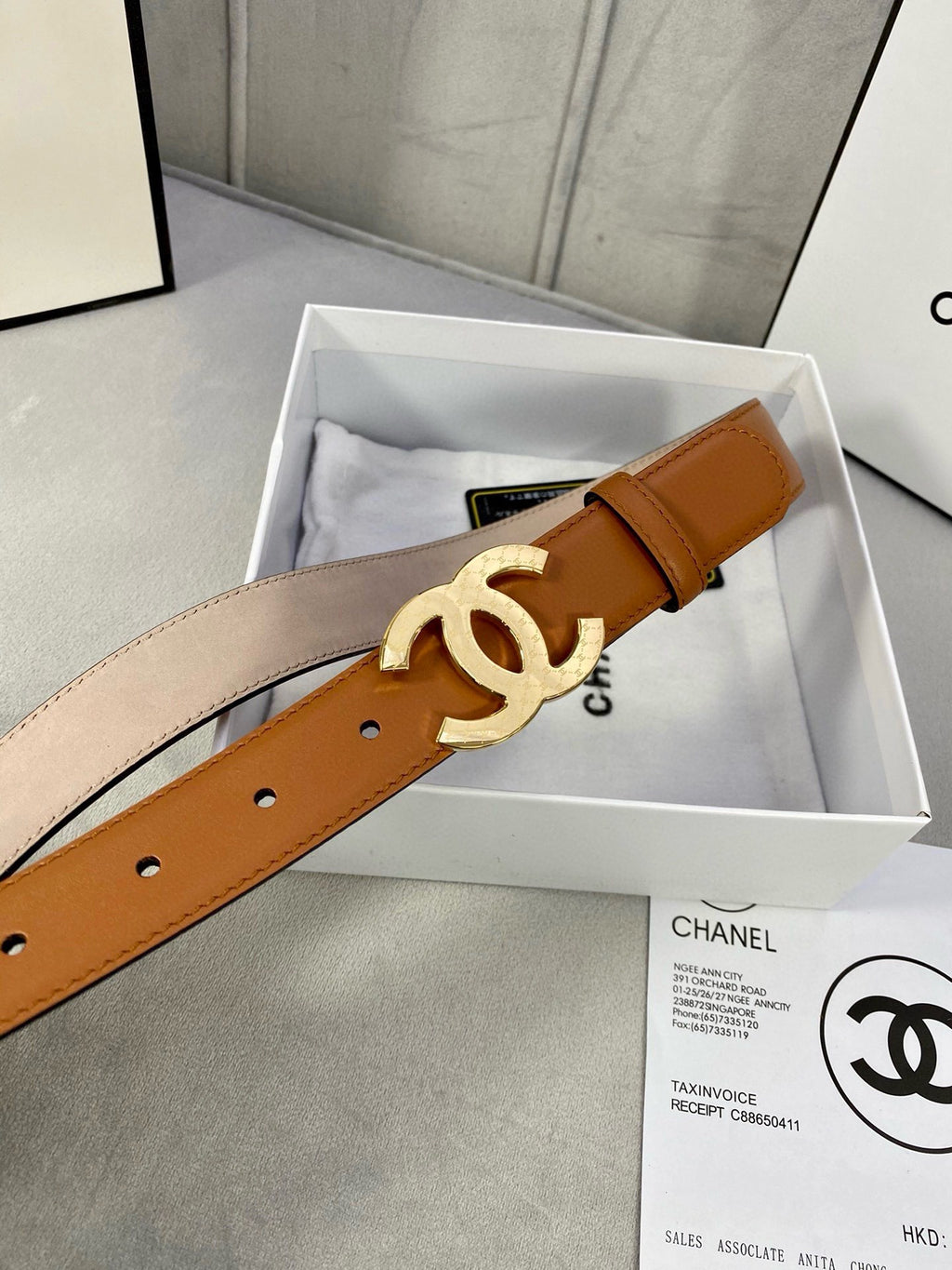 Tan leather belt with gold-tone CC logo buckle and punched adjustment holes