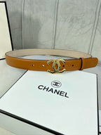 Tan leather belt with gold-tone CC buckle, shown across a white gift box