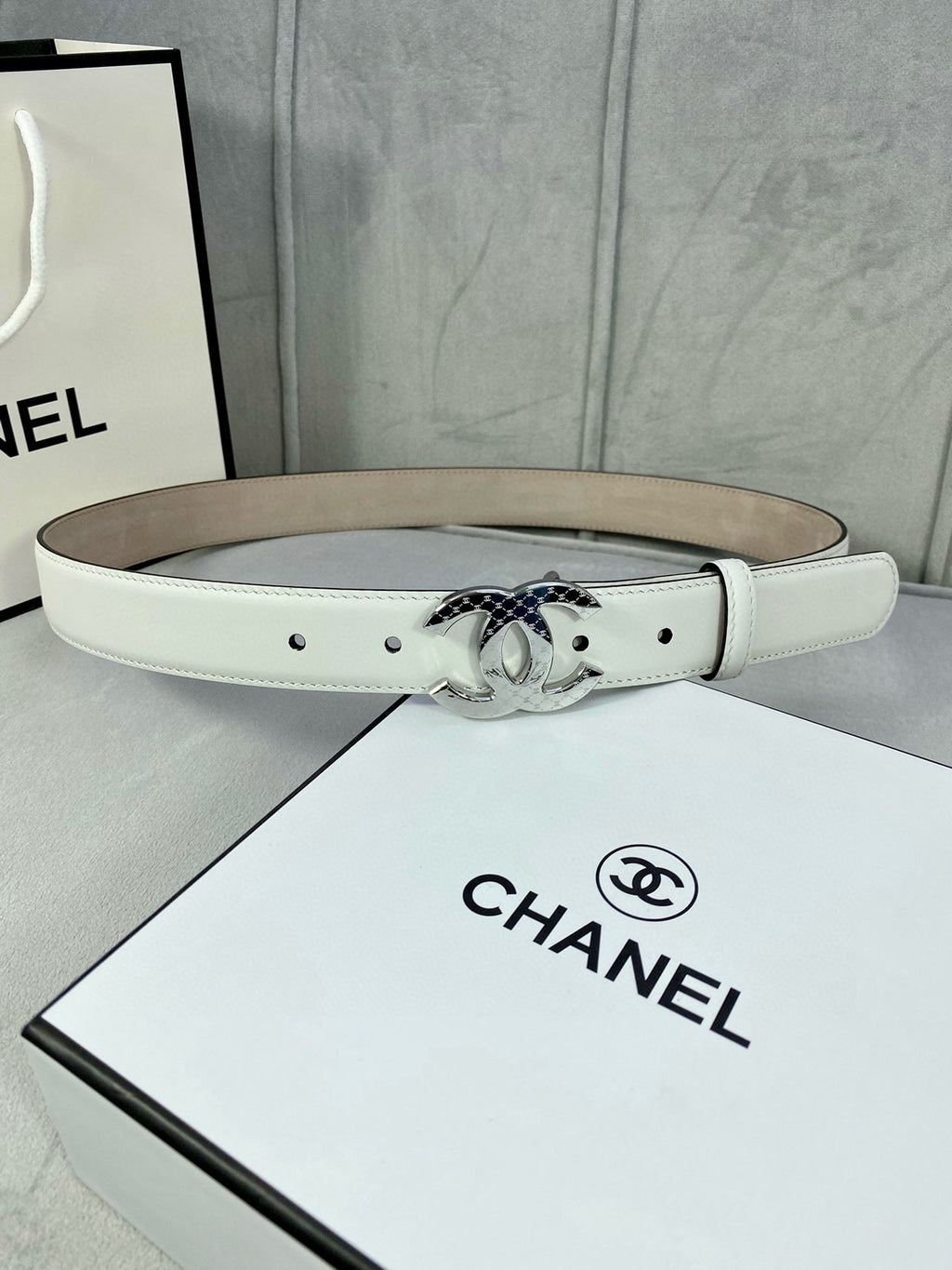 White leather Chanel belt with silver-toned CC buckle on display