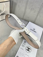 White leather belt with CC buckle resting on a product box