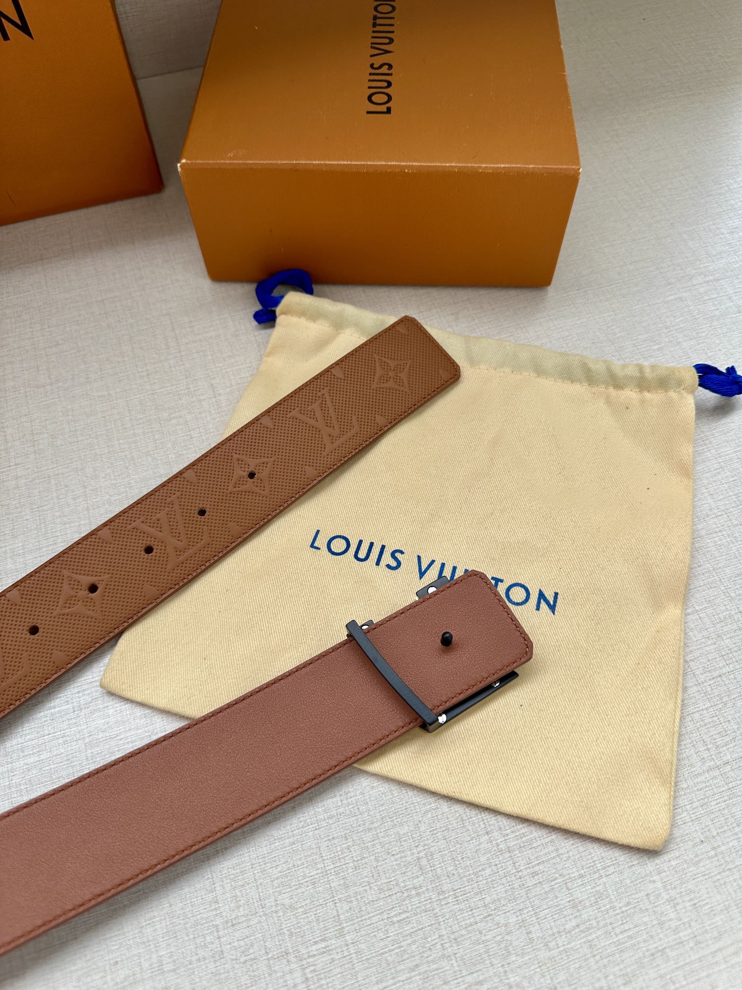 Tan Louis Vuitton belt with monogram texture, punched holes, and buckle