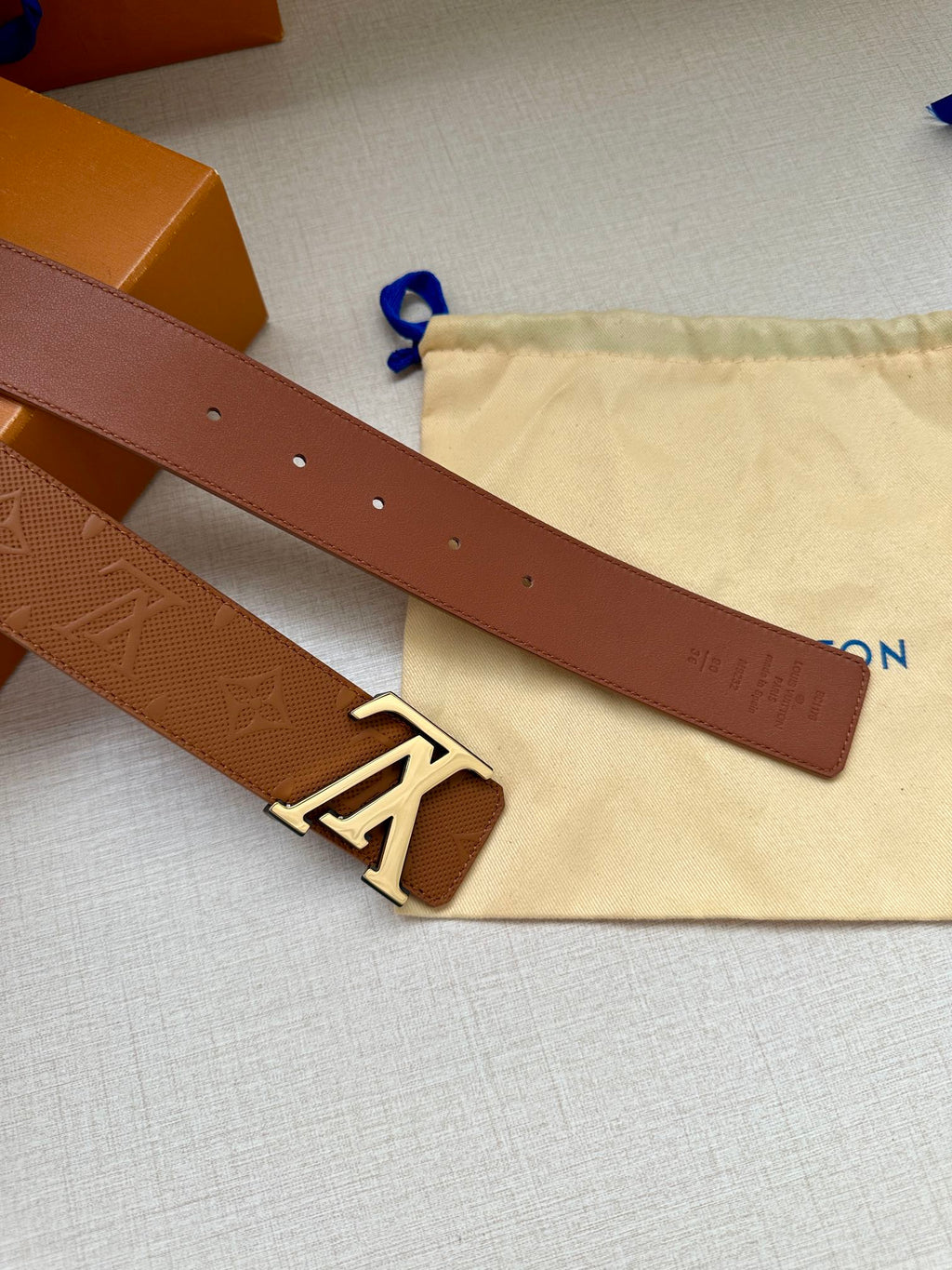 Brown Louis Vuitton belt strap with punched holes and gold-toned LV buckle