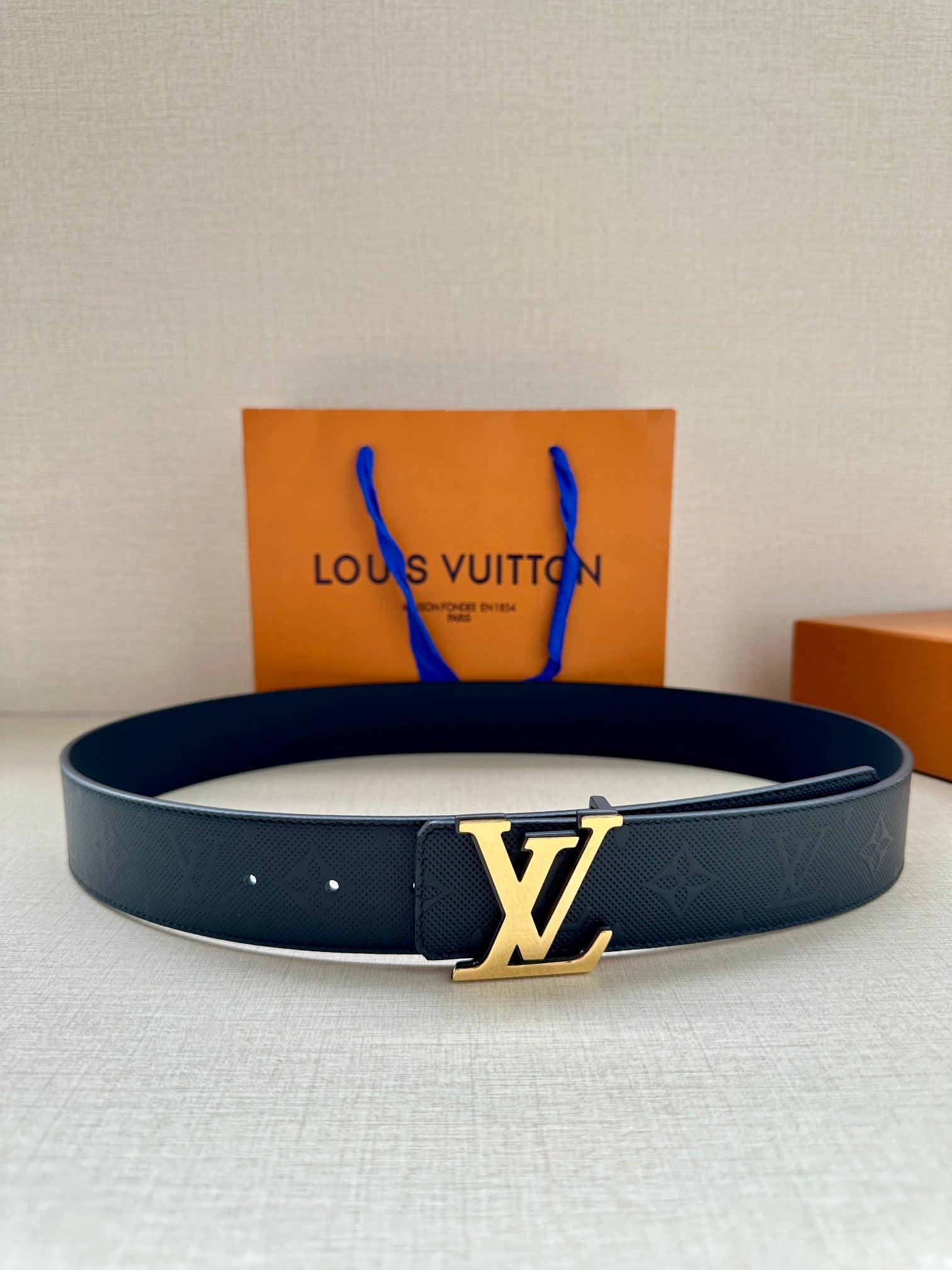 Louis Vuitton leather belt in dark navy with gold-tone LV buckle and embossed texture