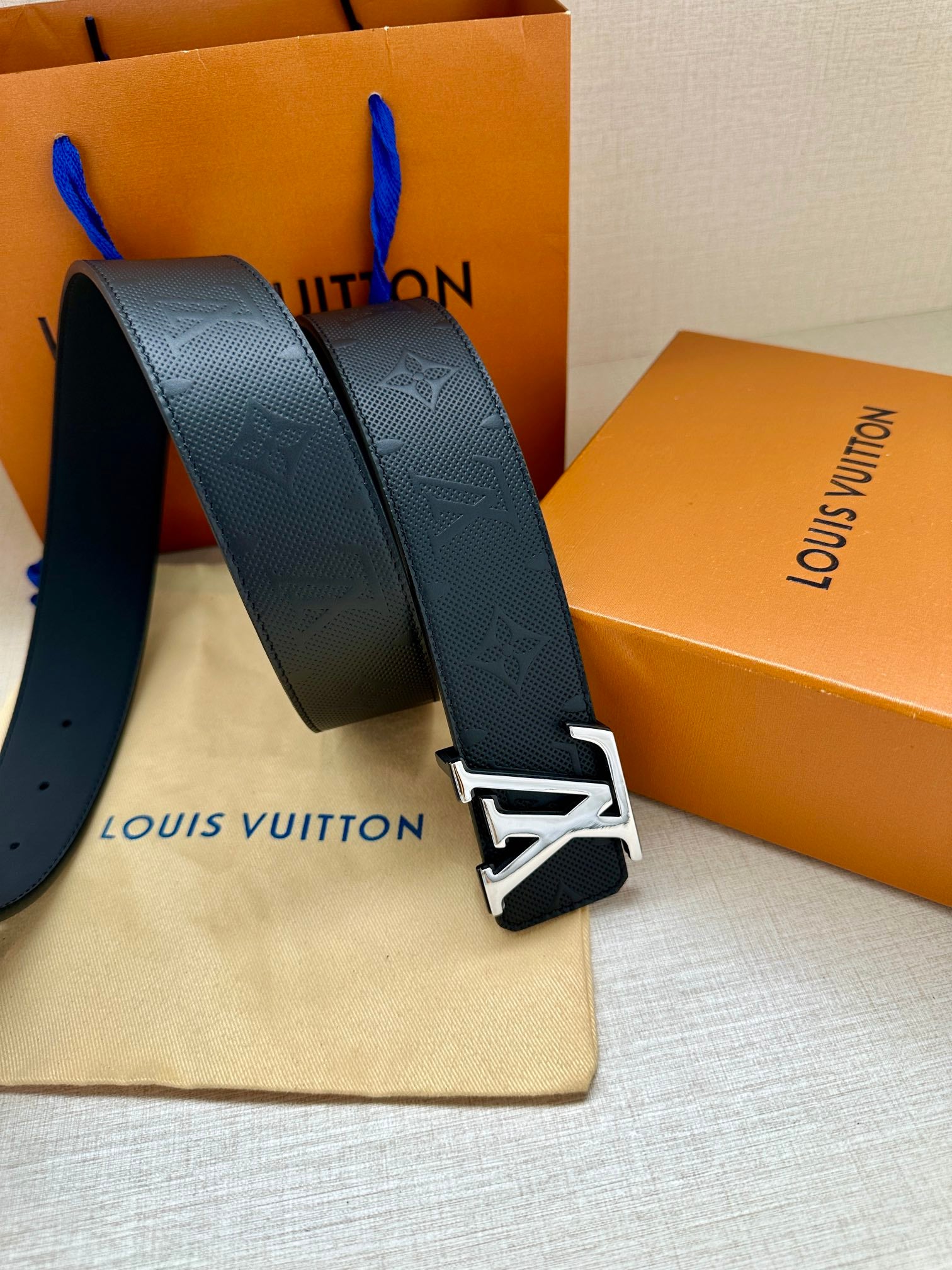 Louis Vuitton belt front view: dark navy embossed strap and oversized gold-tone LV buckle