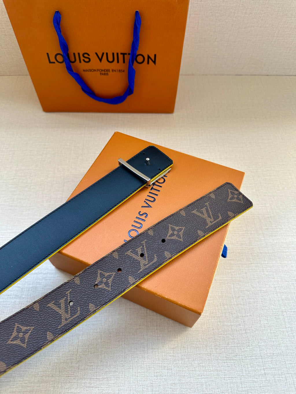 Louis Vuitton monogram belt with blue edge trim and gold buckle, unrolled