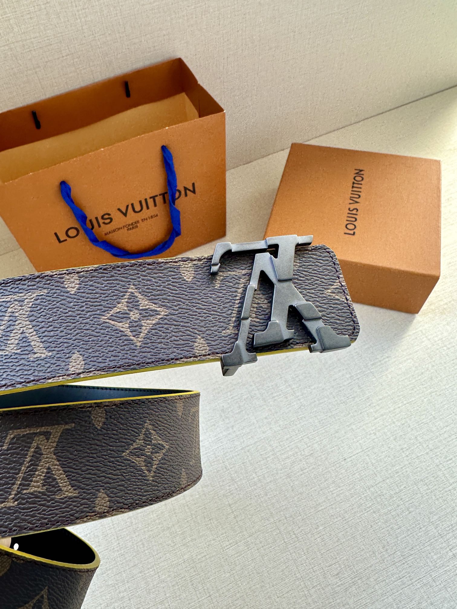 Louis Vuitton monogram belt close-up with metal buckle and yellow-trim edges