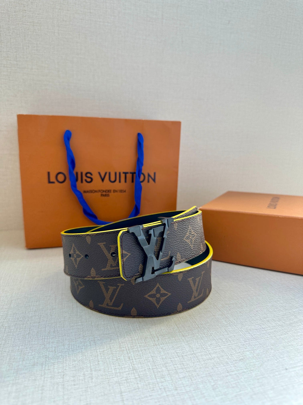 Louis Vuitton belt with monogram pattern, dark strap, gold buckle, and yellow trim
