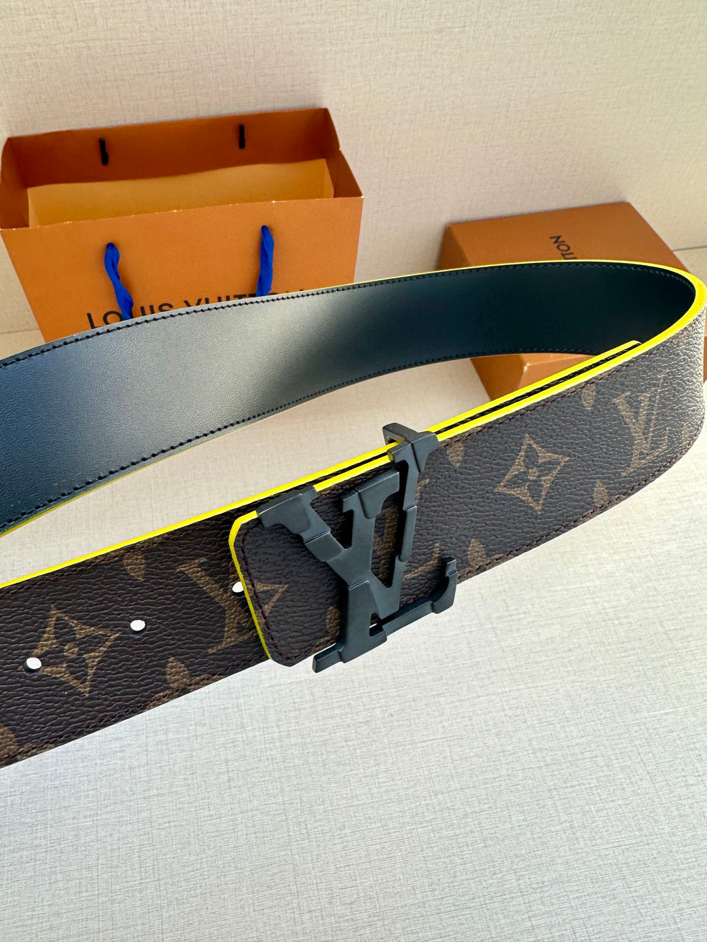 Louis Vuitton belt with monogram strap and close-up gold buckle with yellow edge