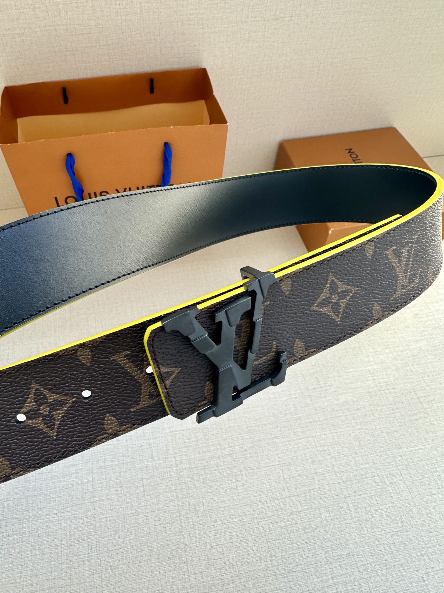 Louis Vuitton belt with monogram strap and close-up gold buckle with yellow edge