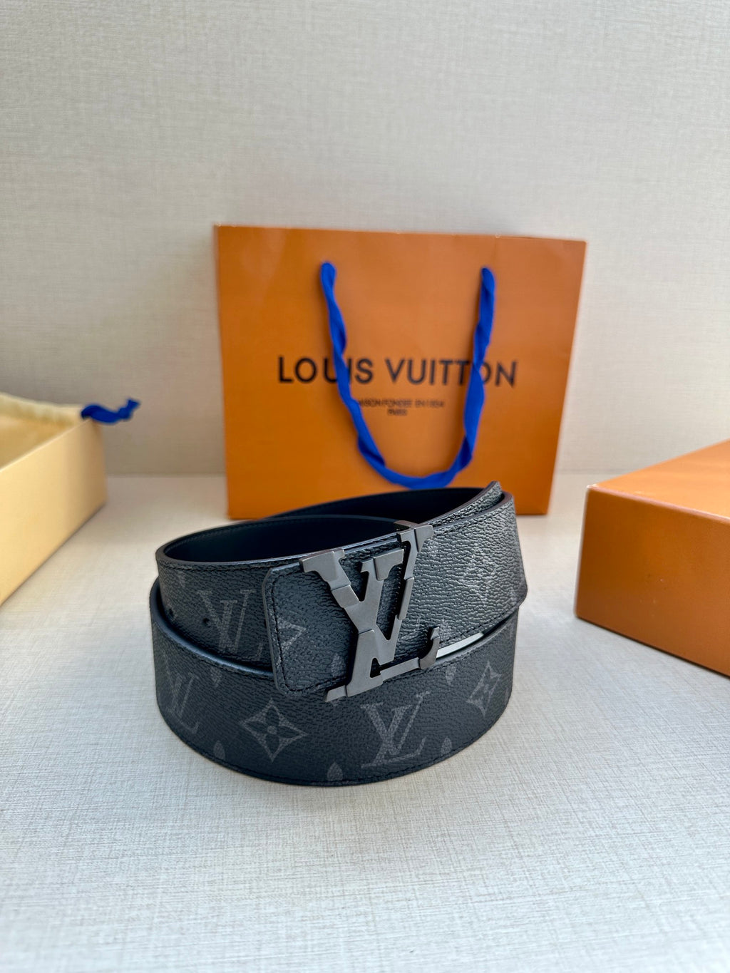 Dark monogram leather belt with silver-tone buckle on a flat strap, front view