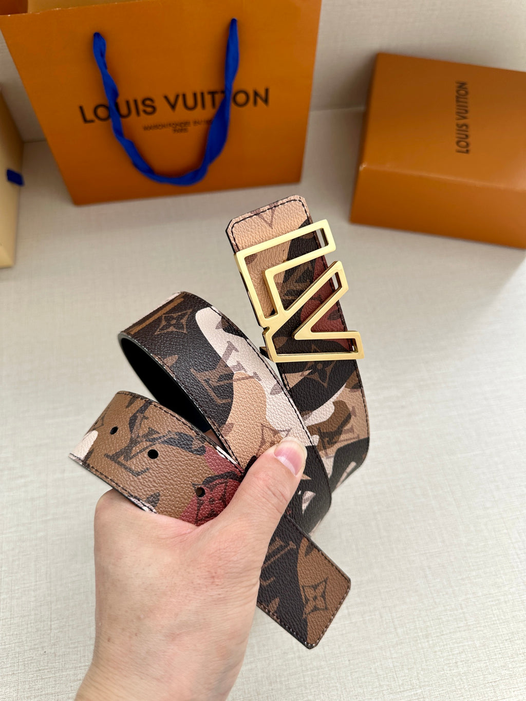 Designer belt with printed logo-style strap and oversized gold-tone LV buckle