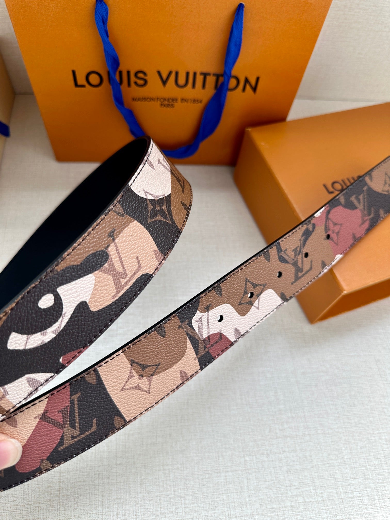 Designer belt strap close-up with tan, brown, and dark print pattern