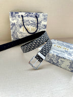 Dior belt with navy patterned strap and silver buckle, laid beside a Dior bag